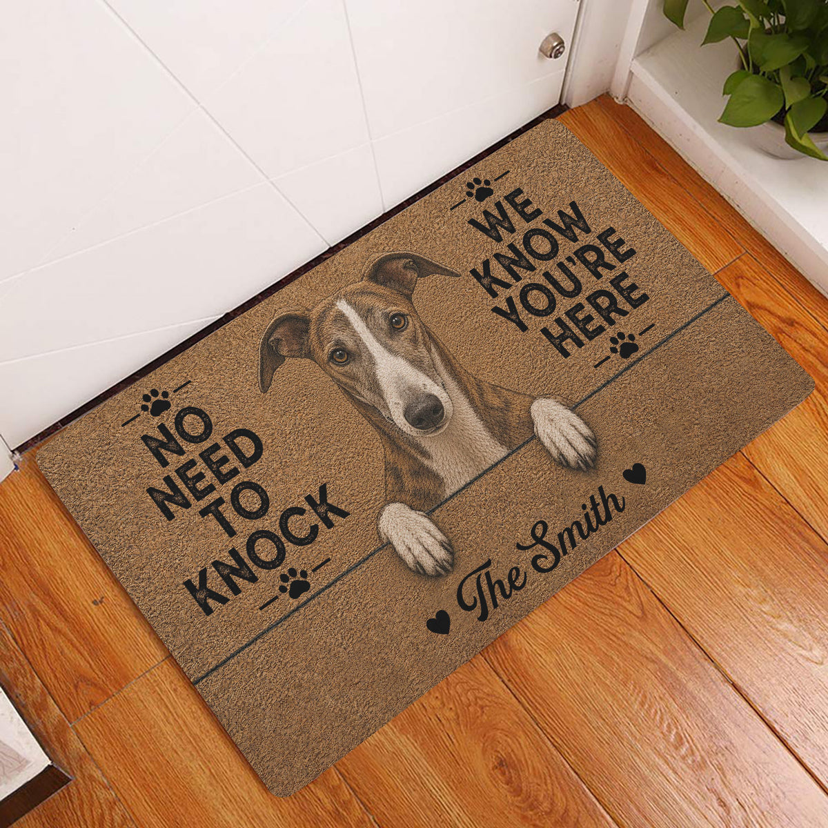 Greyhound entryway rug displayed beside a white door on warm wood flooring