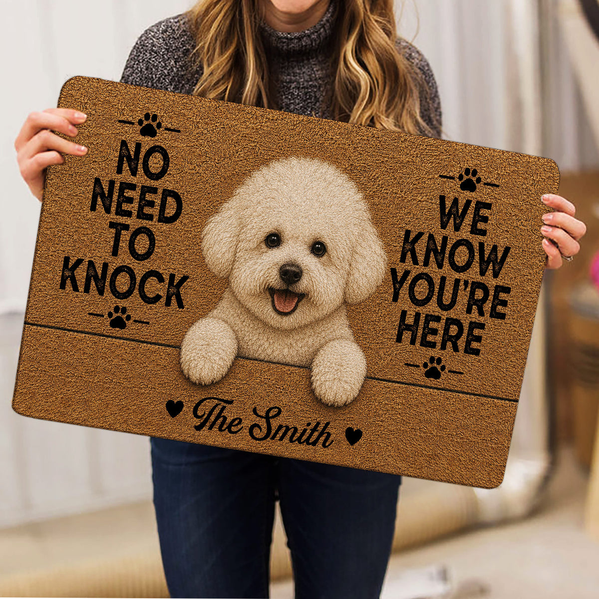 Person holding a Bichon Frise doormat featuring a fluffy white dog, paw prints and a cheerful entryway design