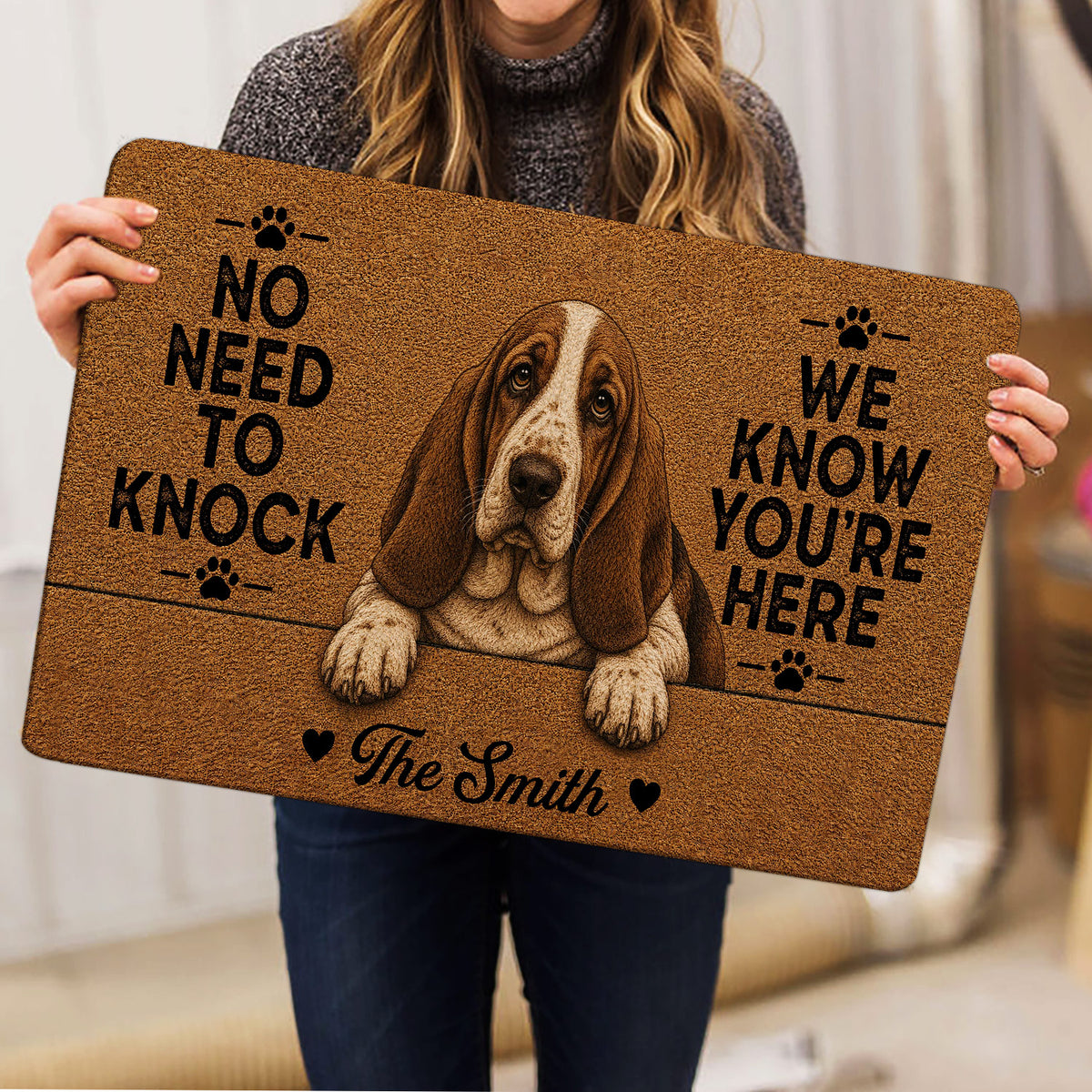 Person holding a Basset Hound doormat featuring a realistic dog portrait and playful black lettering