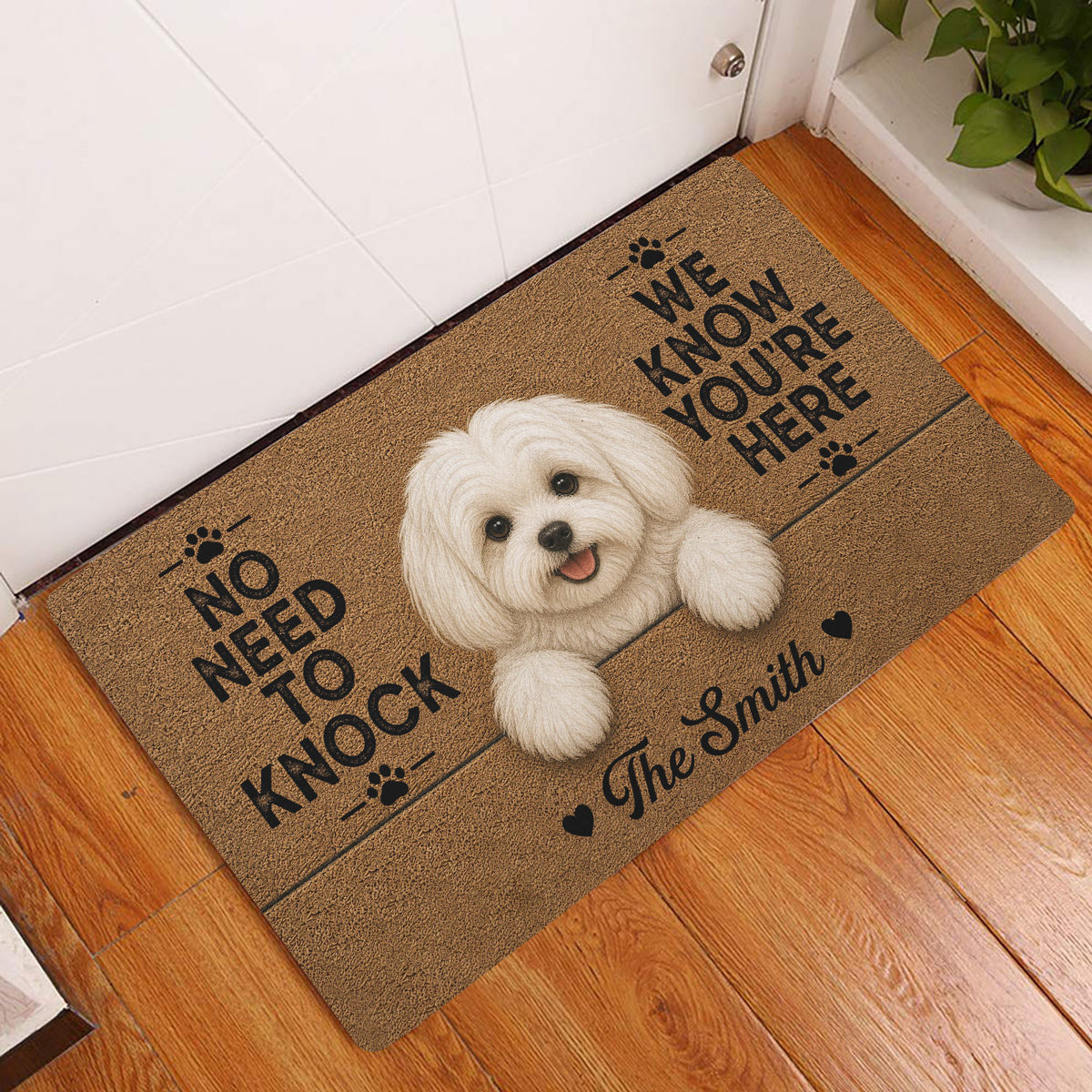 Maltese dog doormat displayed at a home entryway on a warm wood floor beside a white door