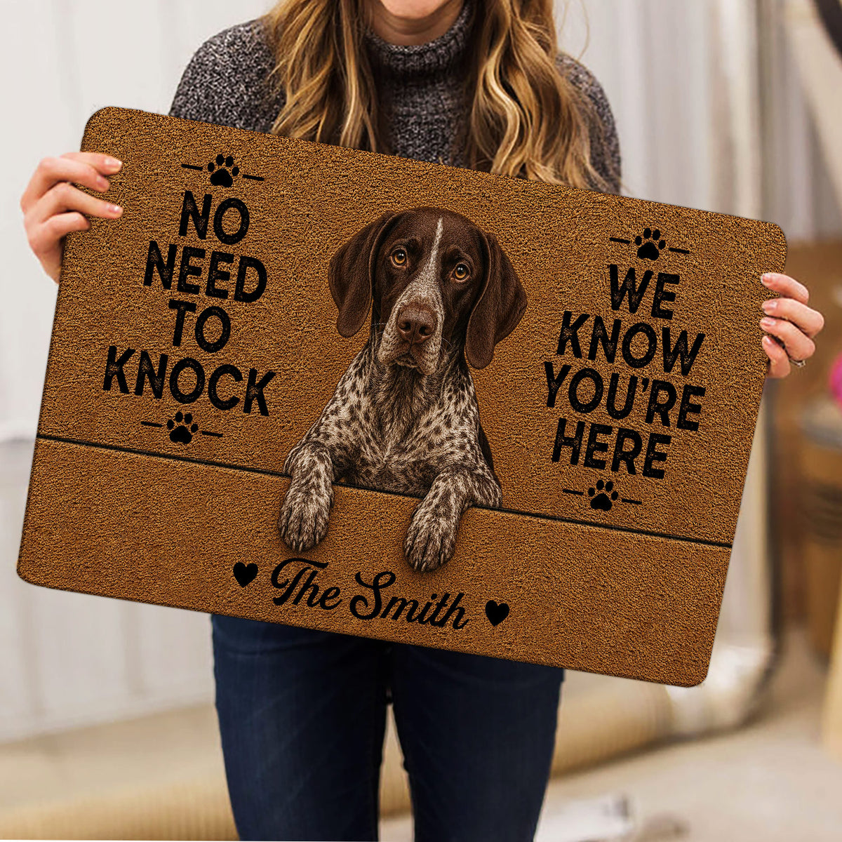 Person holding a German Shorthaired Pointer doormat featuring a realistic dog portrait and humorous welcome message.
