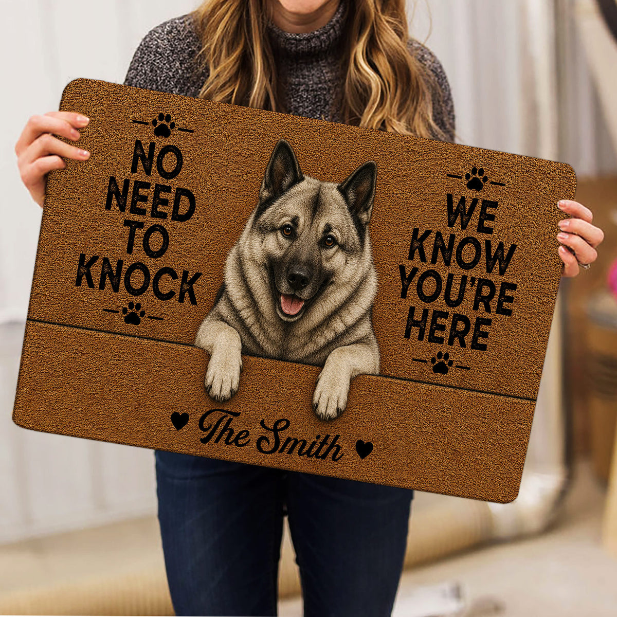 Norwegian Elkhound doormat held indoors, showing the realistic dog artwork and welcoming paw-print design