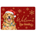 Golden retriever wearing a Santa hat and Christmas lights on a red snowflake doormat