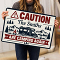 Person holding a vintage camping doormat featuring an RV, mountains, trees and campfire illustration