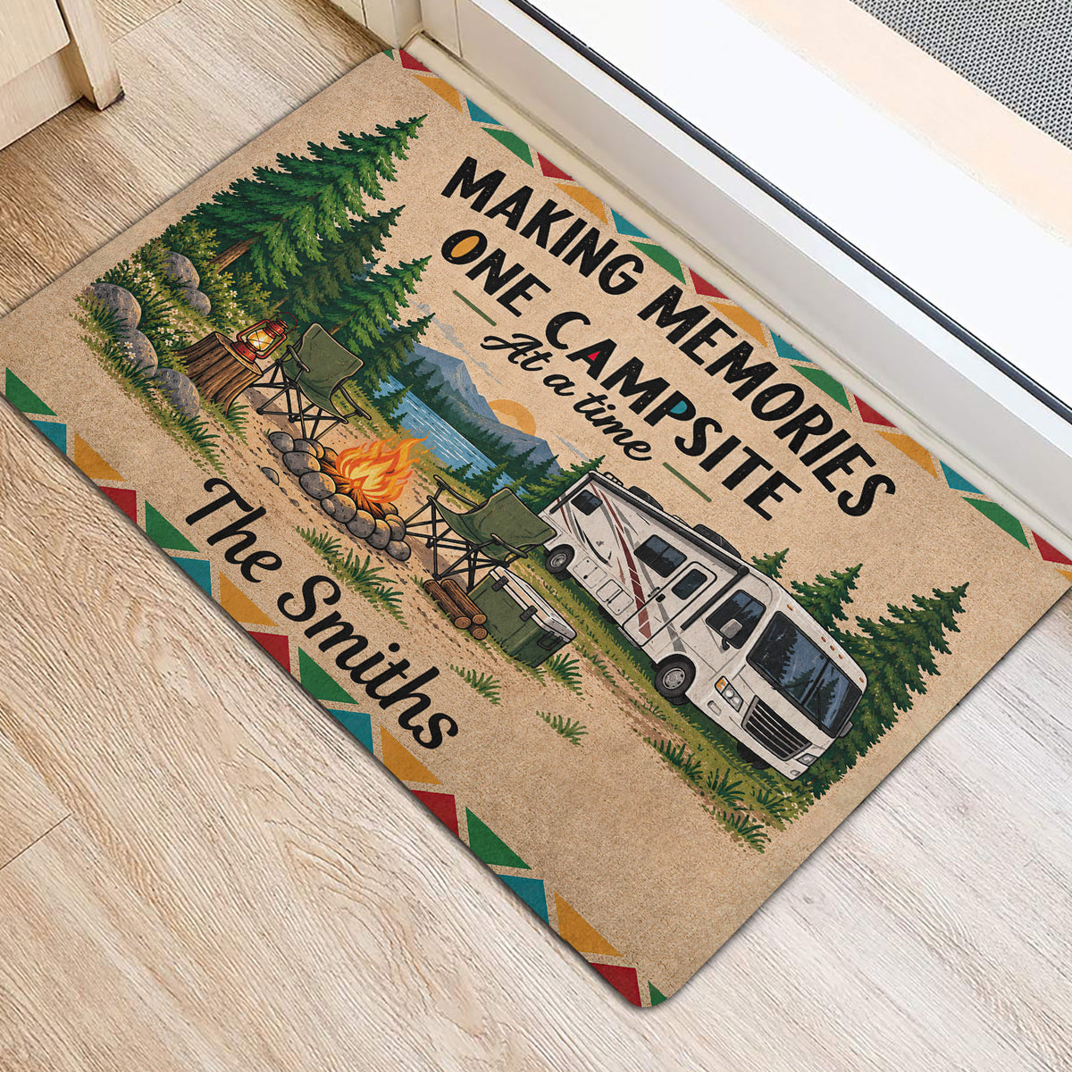 Camping doormat placed near a doorway, featuring pine trees, campfire, lake, mountains, and RV artwork