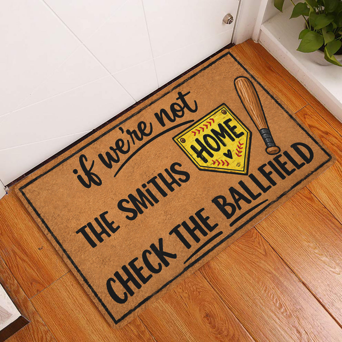 Softball doormat displayed in an entryway on a wood floor beside a white door