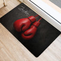 Red boxing glove design displayed on a dark doormat beside an interior doorway