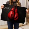 Person holding a dark boxing glove doormat featuring vivid red gloves
