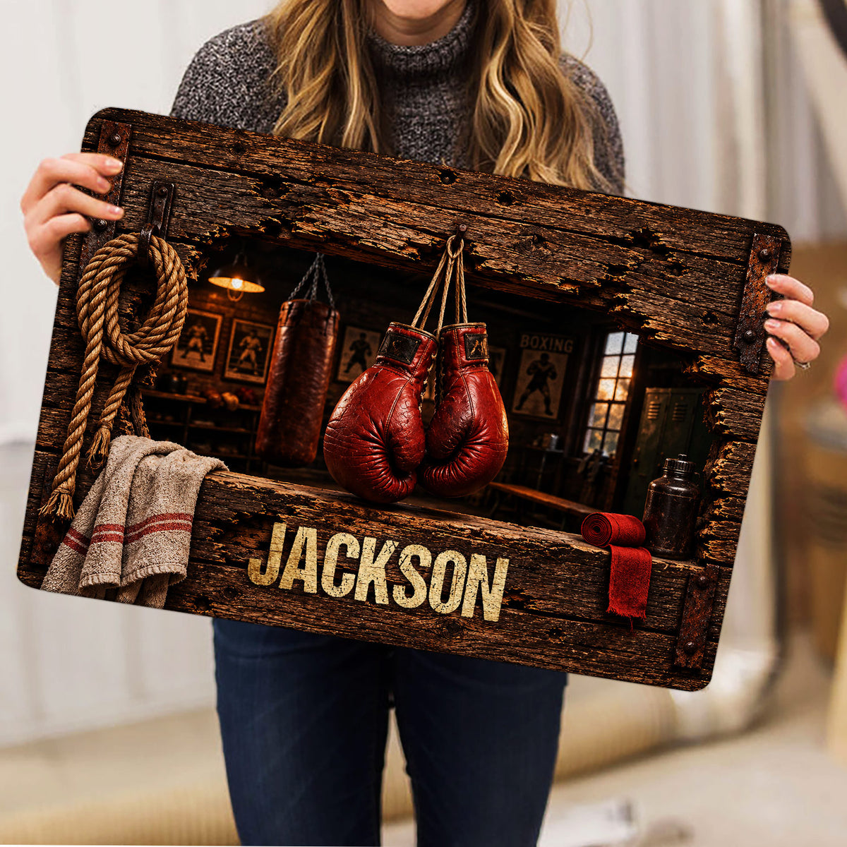 Boxing rug held indoors, displaying red gloves, punching bag, rope, and vintage gym artwork