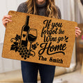 Person holding a wine-themed doormat featuring a bottle, wine glass, grapes, and script artwork