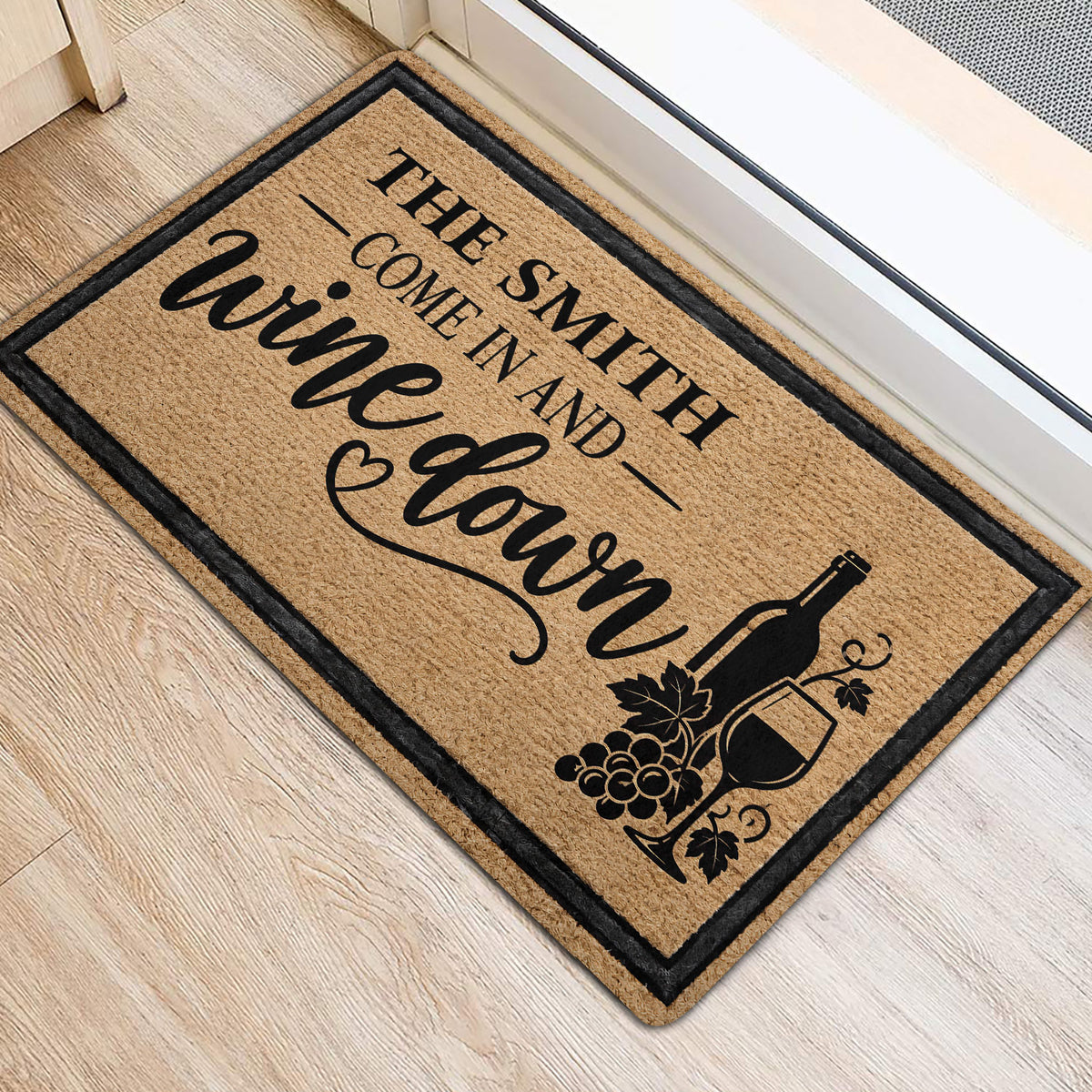 Wine bottle and grape doormat styled at an indoor doorway with wood flooring