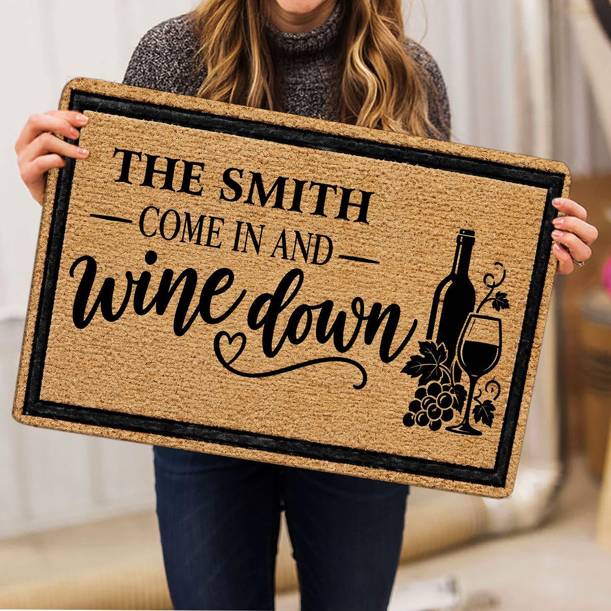Wine doormat held indoors showing bottle, wine glass, grape, and welcome artwork