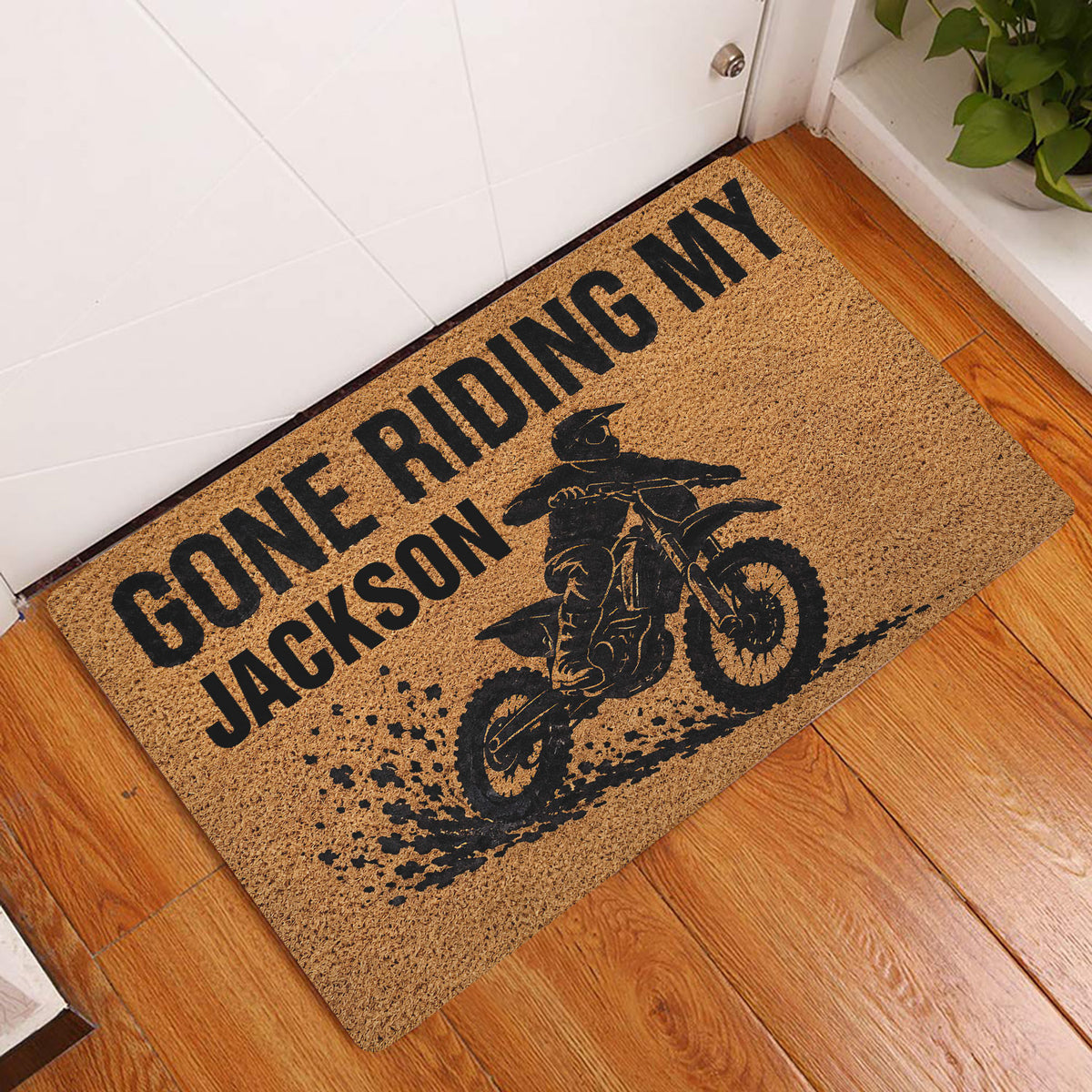 Motocross dirt bike doormat displayed at an indoor entryway beside a white door