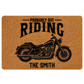 Custom family name biker doormat featuring a vintage black cruiser motorcycle illustration, bold Probably Out Riding quote, warm tan coir-look printed background, rounded corners and personalized surname at bottom.