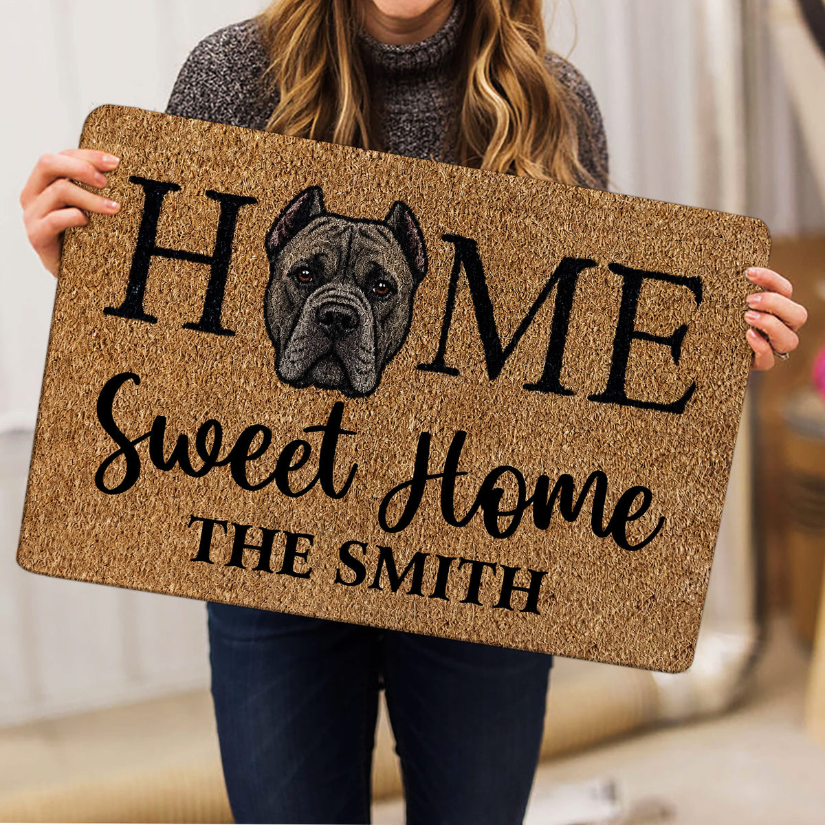 Person holding a Cane Corso doormat featuring a realistic dog portrait and bold black lettering