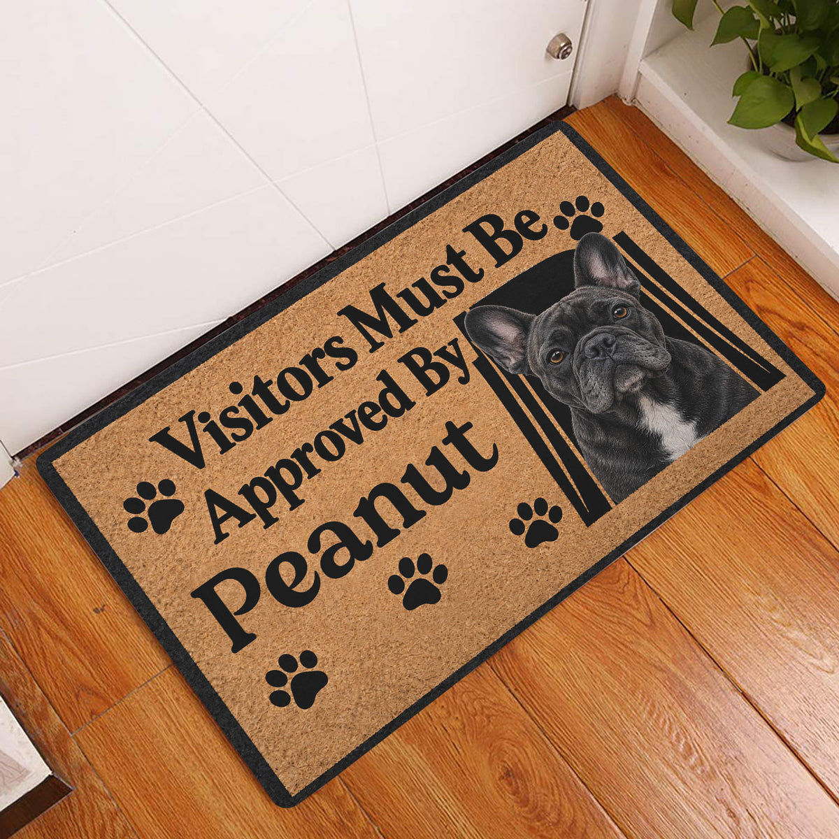French Bulldog entryway doormat displayed on a wood floor beside a white door
