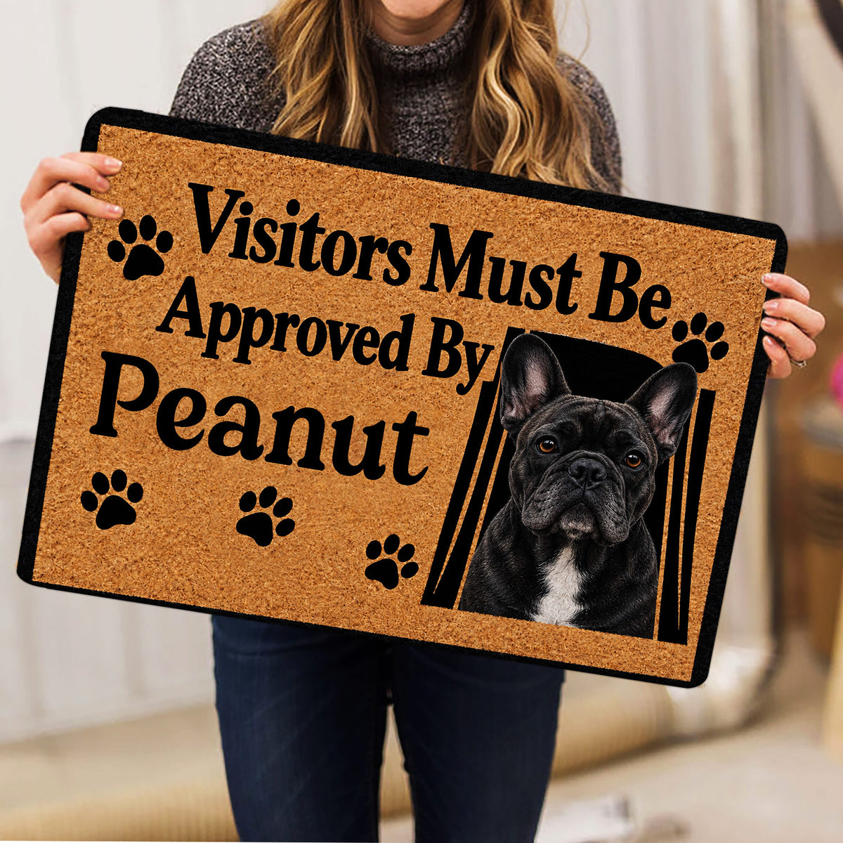 French Bulldog doormat held indoors, showing portrait artwork, paw prints, and bold typography