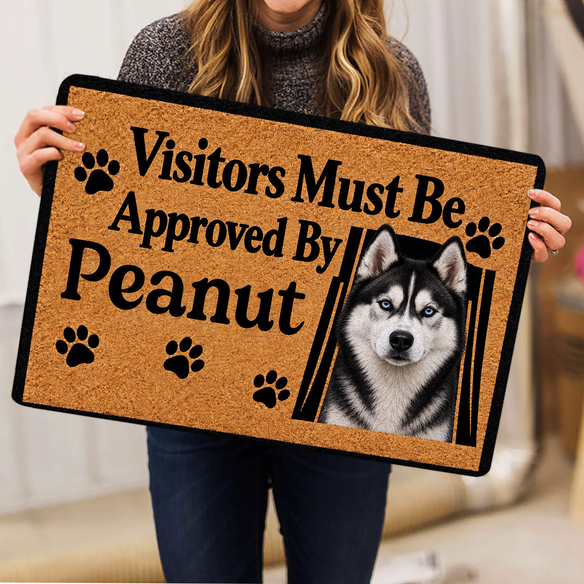 Person holding a Husky doormat with a blue-eyed dog portrait and paw-print artwork