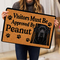 Person holding a Labrador Retriever doormat featuring a black dog portrait and paw print artwork