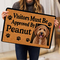 Goldendoodle rug held indoors showing the curly dog artwork, paw prints, black border, and playful entryway design