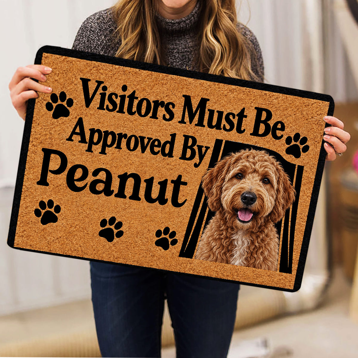 Goldendoodle rug held indoors showing the curly dog artwork, paw prints, black border, and playful entryway design