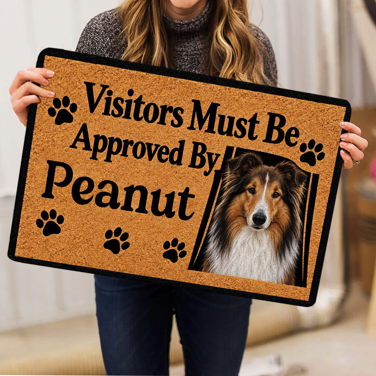 Person holding a Rough Collie doormat featuring a portrait, paw prints, and welcome artwork