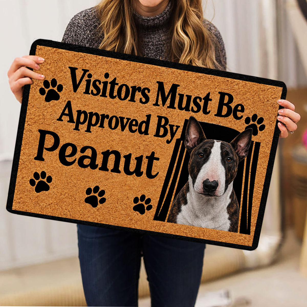 Person holding a Bull Terrier doormat featuring a realistic dog portrait and bold paw print design