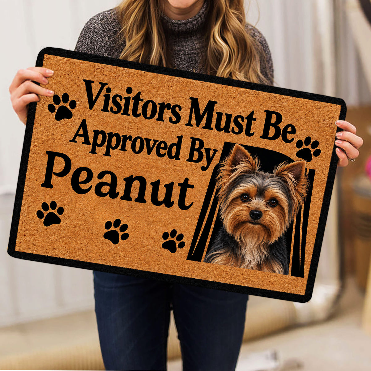 Person holding a tan Yorkie doormat featuring a Yorkshire Terrier portrait and paw prints