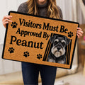 Person holding a Miniature Schnauzer doormat featuring a portrait, paw prints, and bold black lettering