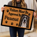 Person holding an American Staffordshire dog doormat with a tan background and black paw print accents