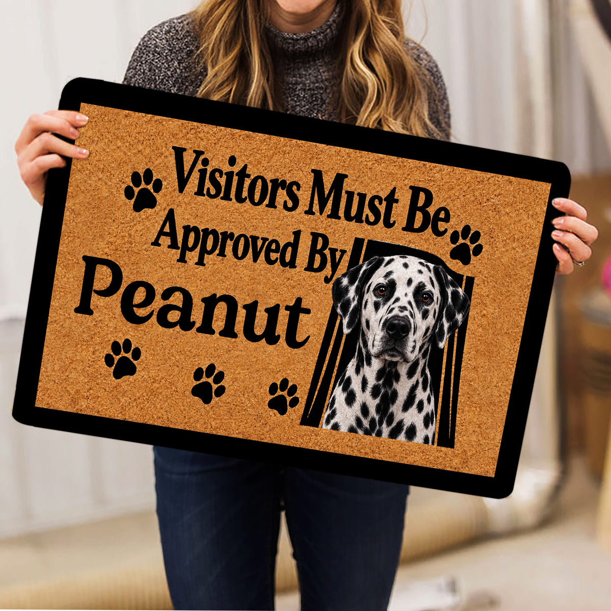 Person holding a Dalmatian doormat featuring a spotted dog portrait and paw print artwork