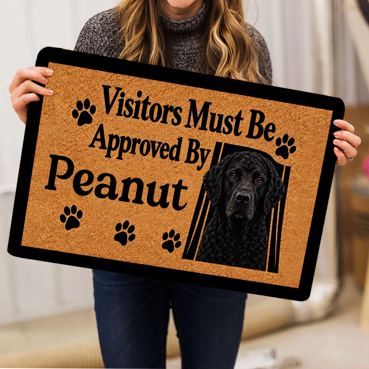 Curly Coated Retriever doormat held indoors, showing the black dog portrait and paw print artwork