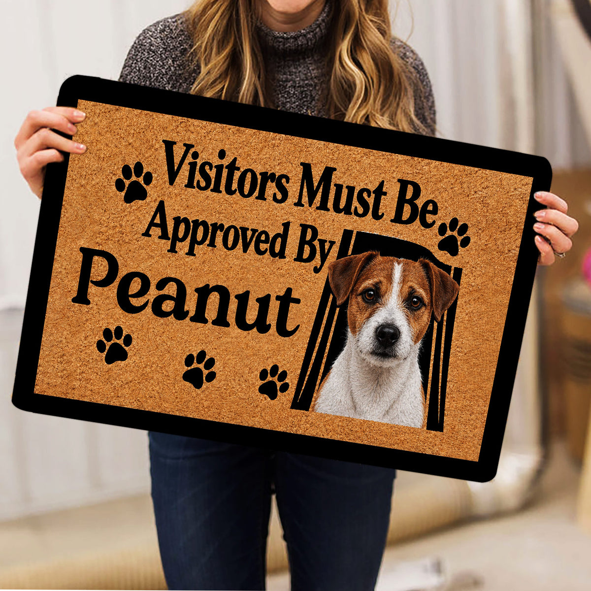 Person holding a Jack Russell doormat featuring a terrier portrait, paw prints, and bold black lettering