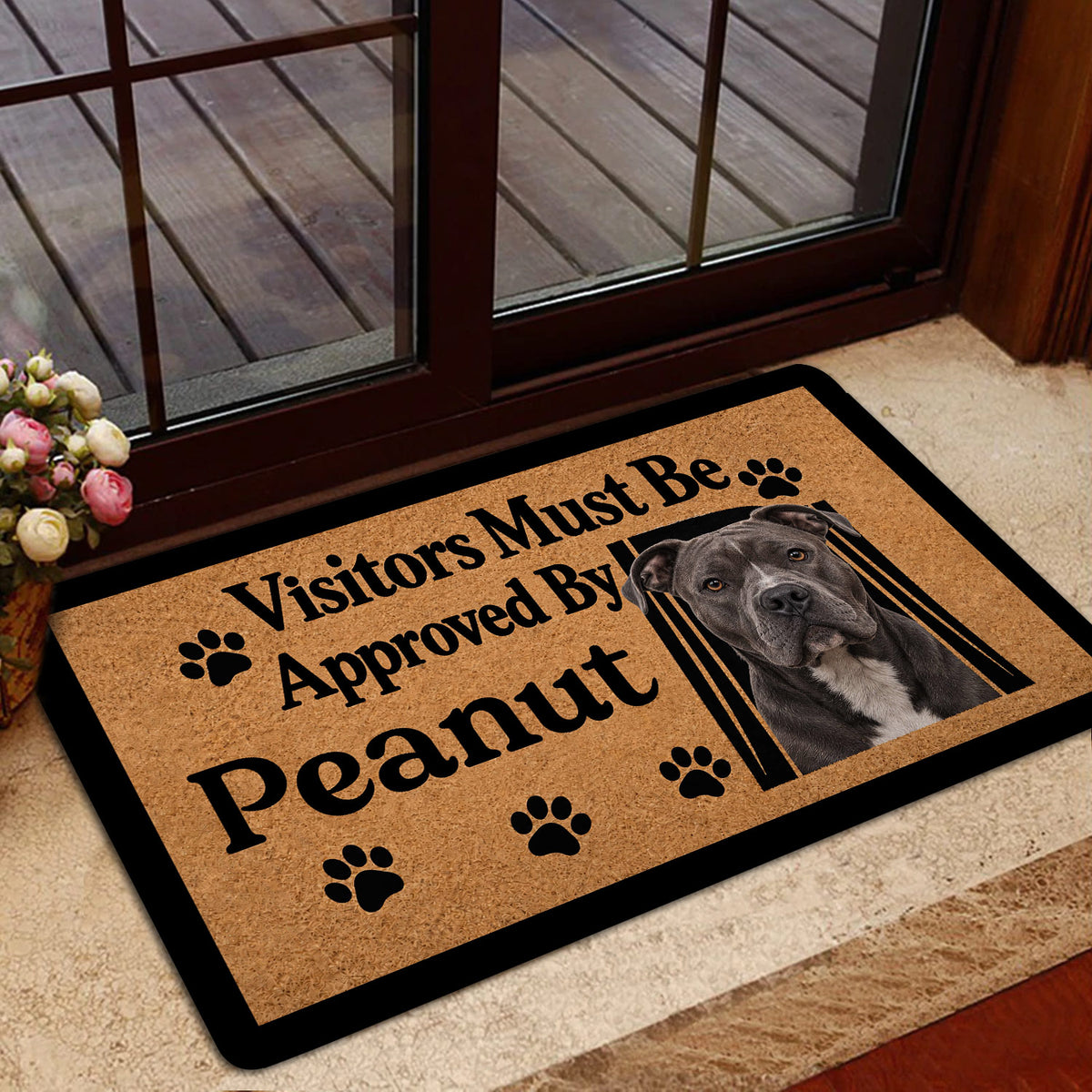 Pitbull doormat styled inside a glass doorway, featuring a tan background, black border, paw prints, and dog artwork