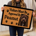 Person holding a Labradoodle doormat showing the curly dog portrait, paw prints, and black lettering
