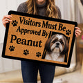 Person holding a Shih Tzu doormat featuring a dog portrait, paw prints, and bold black lettering