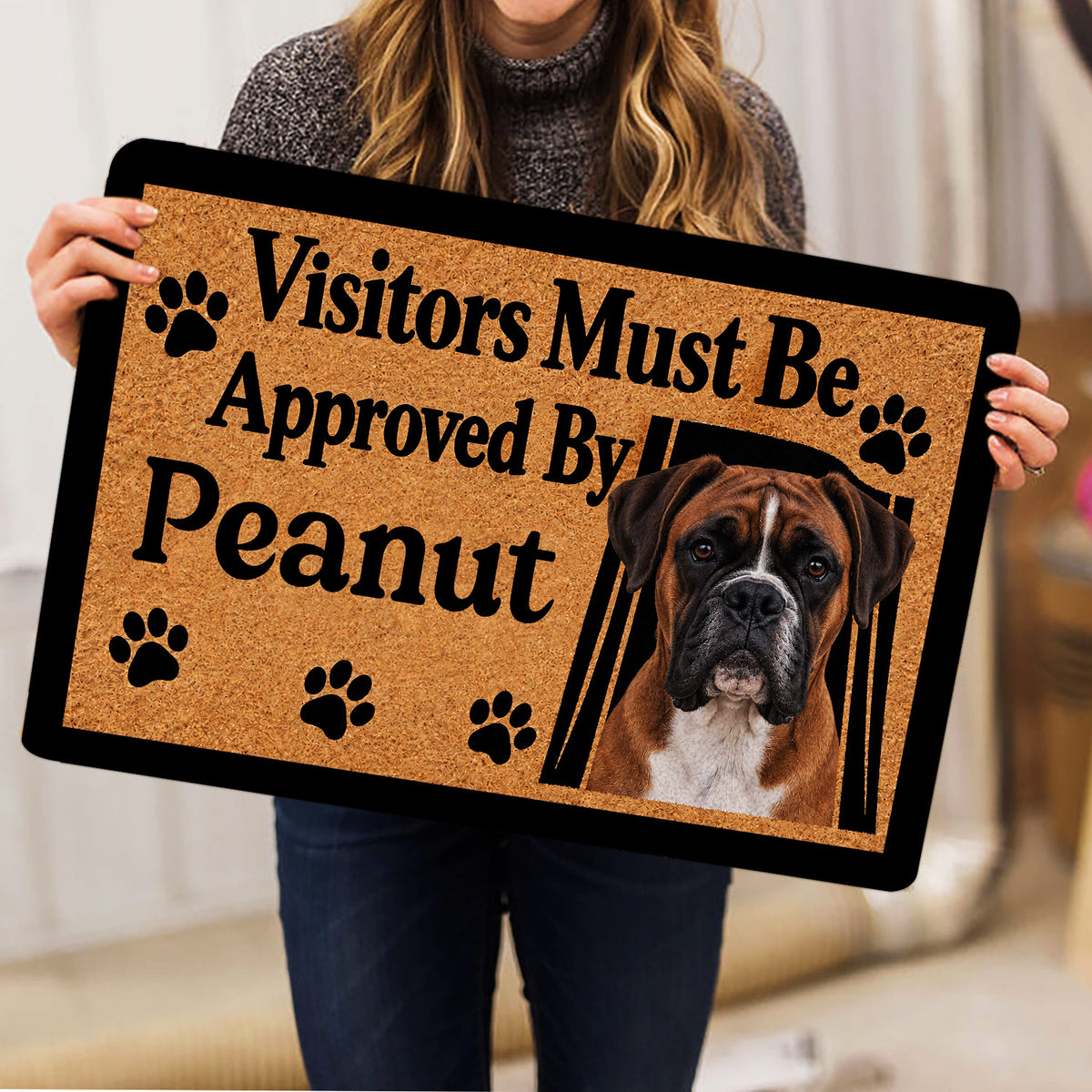 Person holding a Boxer dog doormat featuring a portrait, paw prints, and bold lettering