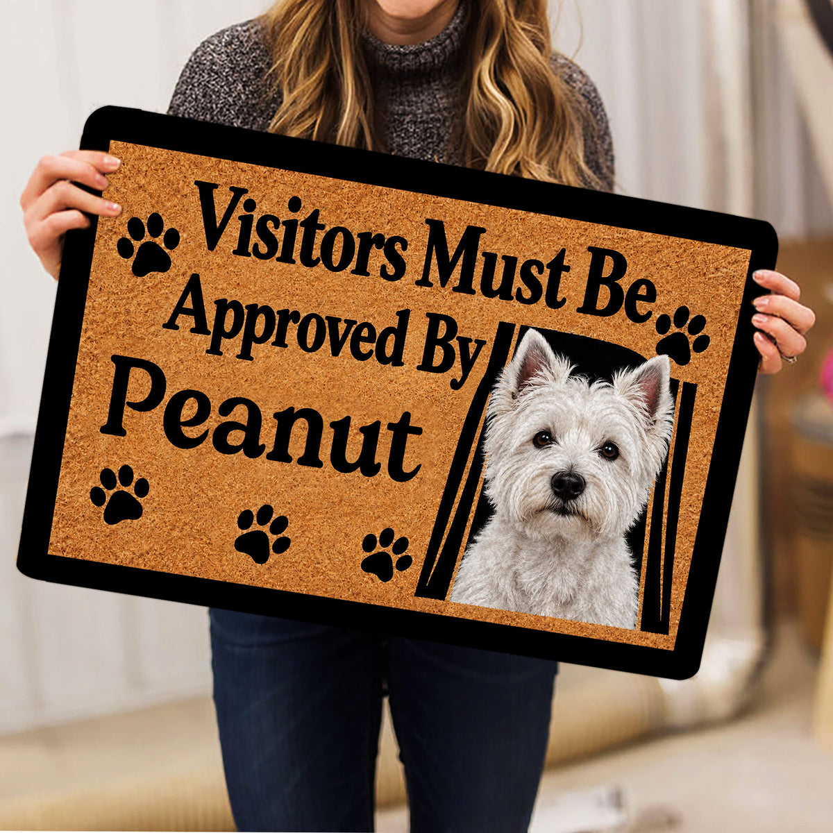 Westie doormat held indoors, showing the white terrier artwork, paw prints and tan textured background