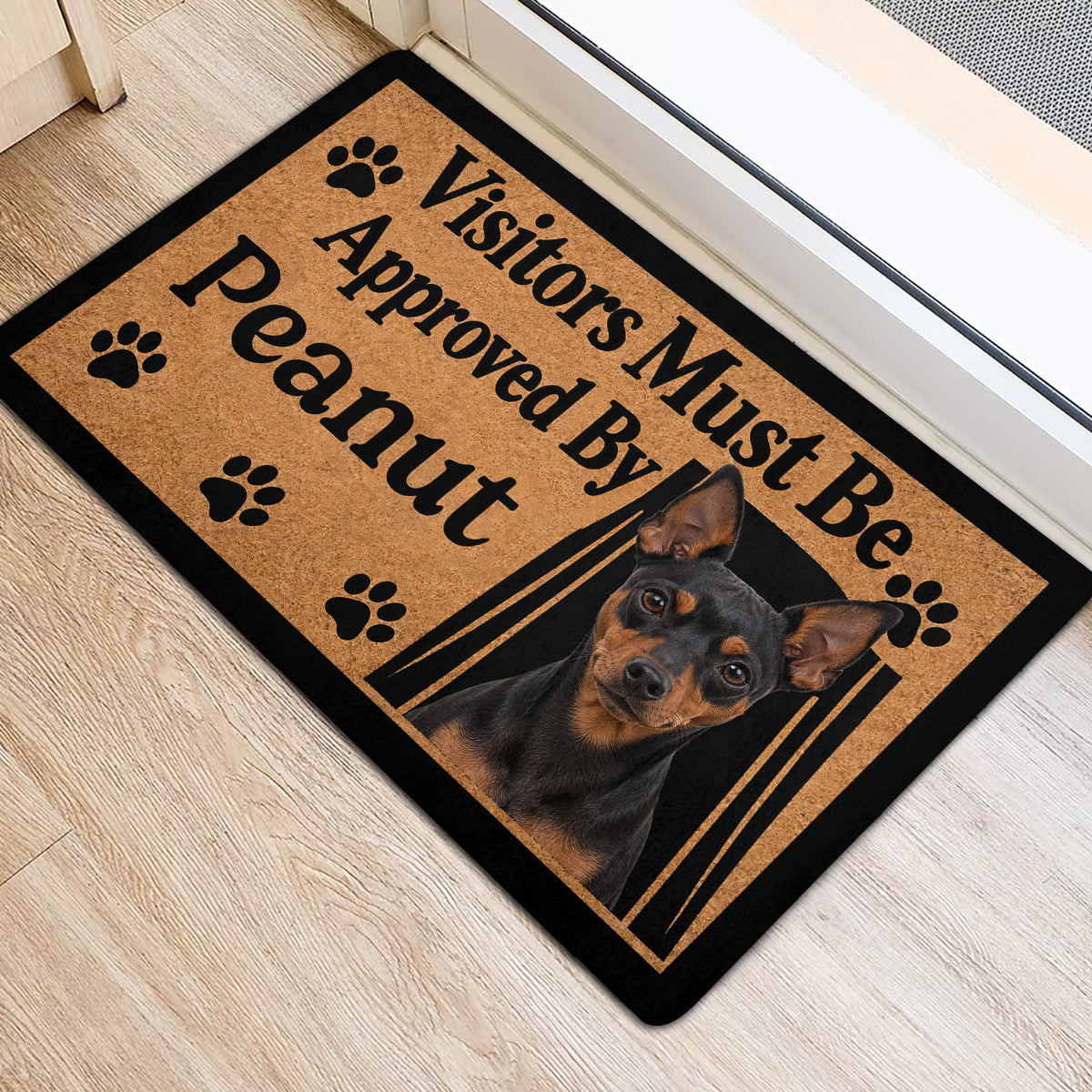 Miniature Pinscher entryway mat with paw prints and dog portrait beside a light-colored doorway