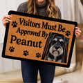 Person holding a Miniature Schnauzer doormat featuring a realistic portrait, paw prints, and tan decorative artwork