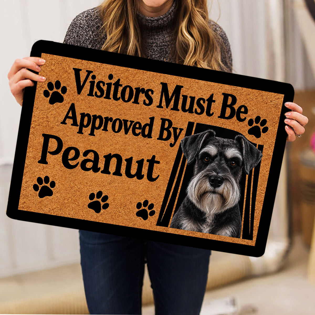 Person holding a Miniature Schnauzer doormat featuring a realistic portrait, paw prints, and tan decorative artwork