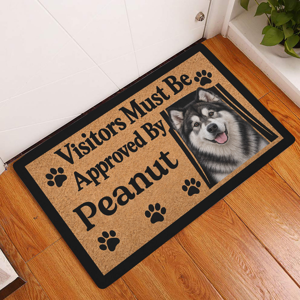 Alaskan Malamute entryway doormat displayed beside a white door on a warm wood floor