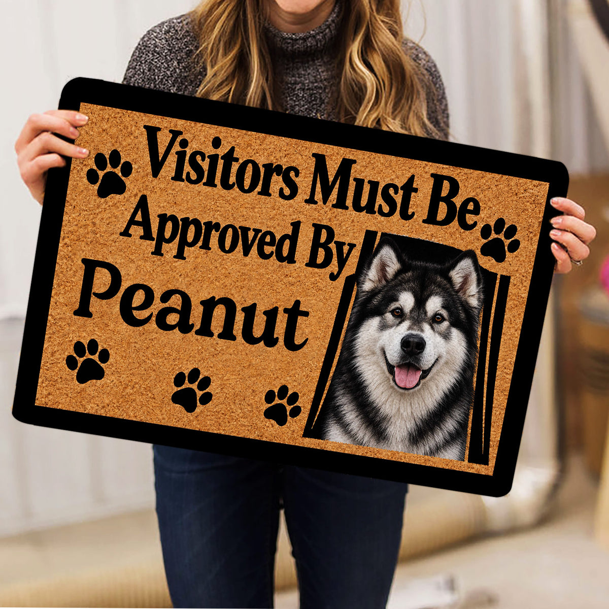 Alaskan Malamute doormat held indoors, showing the detailed dog portrait, paw prints, and bold lettering