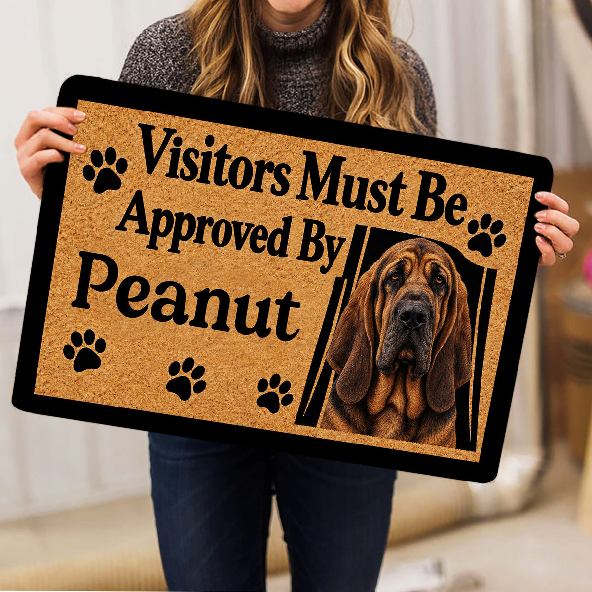 Person holding a bloodhound doormat featuring a realistic portrait and paw print design