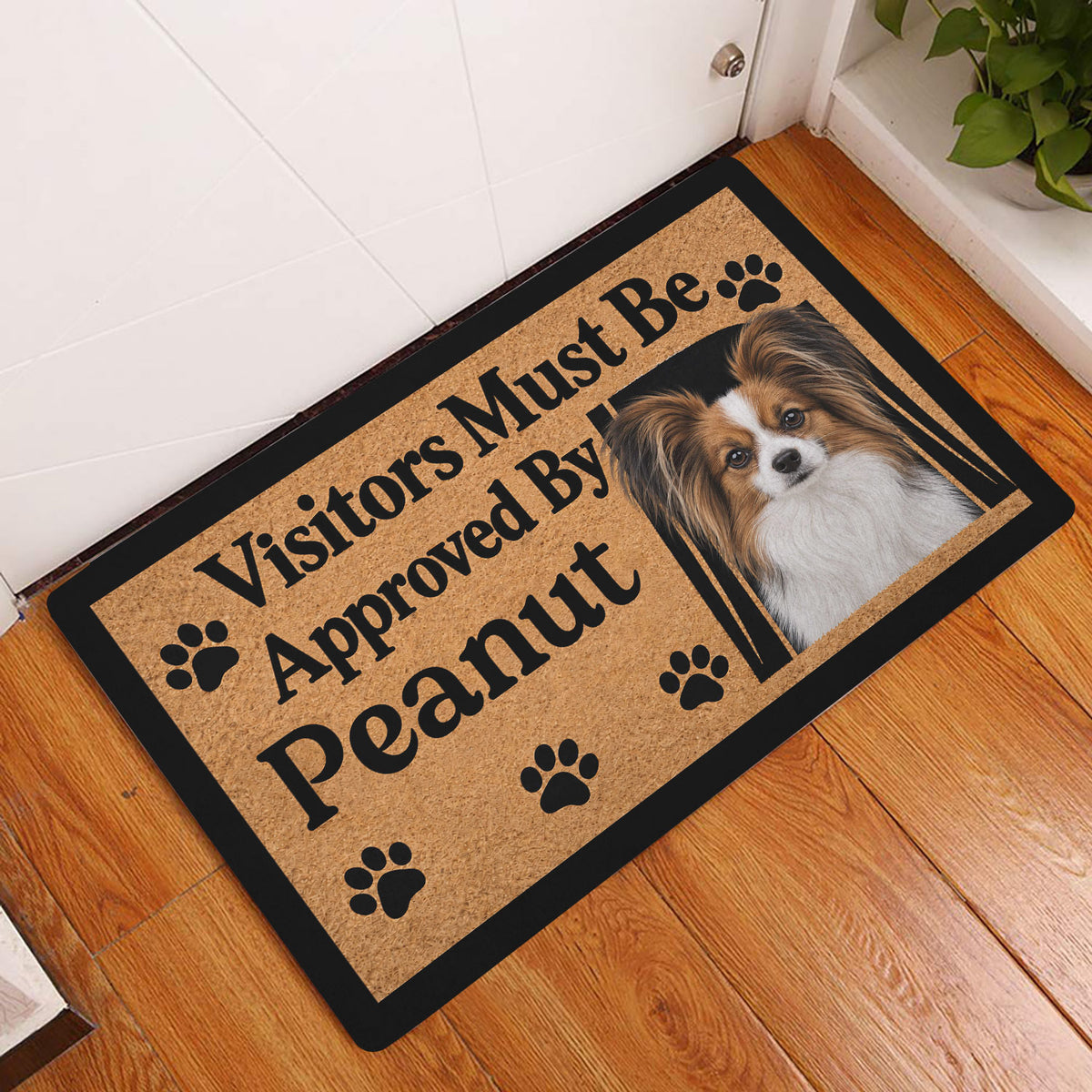 Papillon dog entryway mat displayed on a wood floor beside a white door