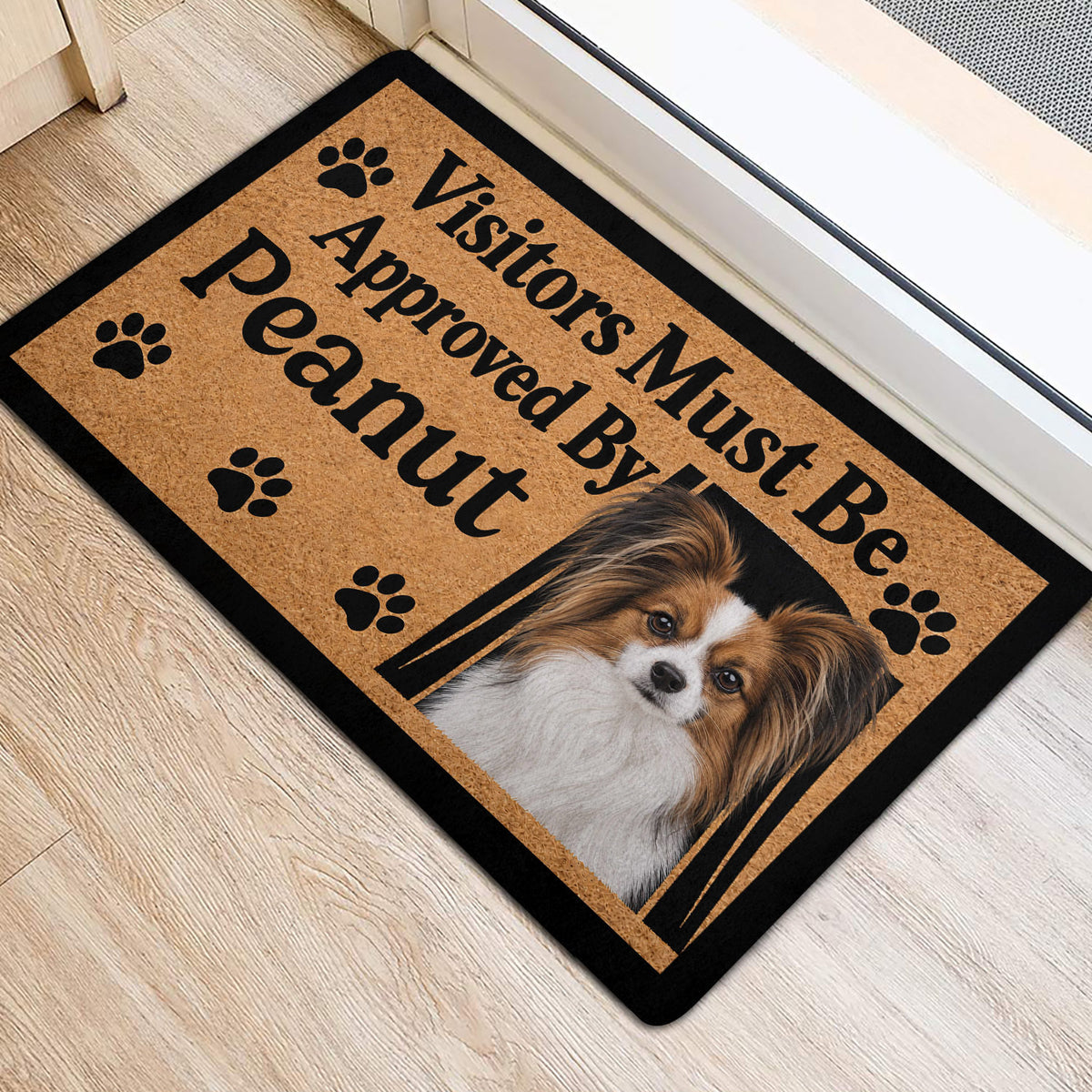 Papillon dog door mat placed near an interior doorway on a light wood floor