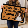 Person holding a Papillon dog doormat featuring a portrait, paw prints, and bold black lettering