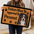 Australian Shepherd doormat held indoors, showing the dog portrait, paw prints, and tan decorative background