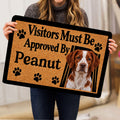 Person holding a Brittany Spaniel doormat featuring a dog portrait, paw prints, and tan artwork