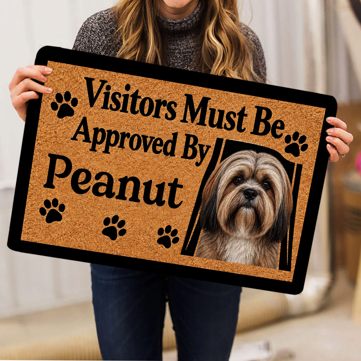Person holding a Lhasa Apso dog doormat featuring a portrait, paw prints, and bold lettering